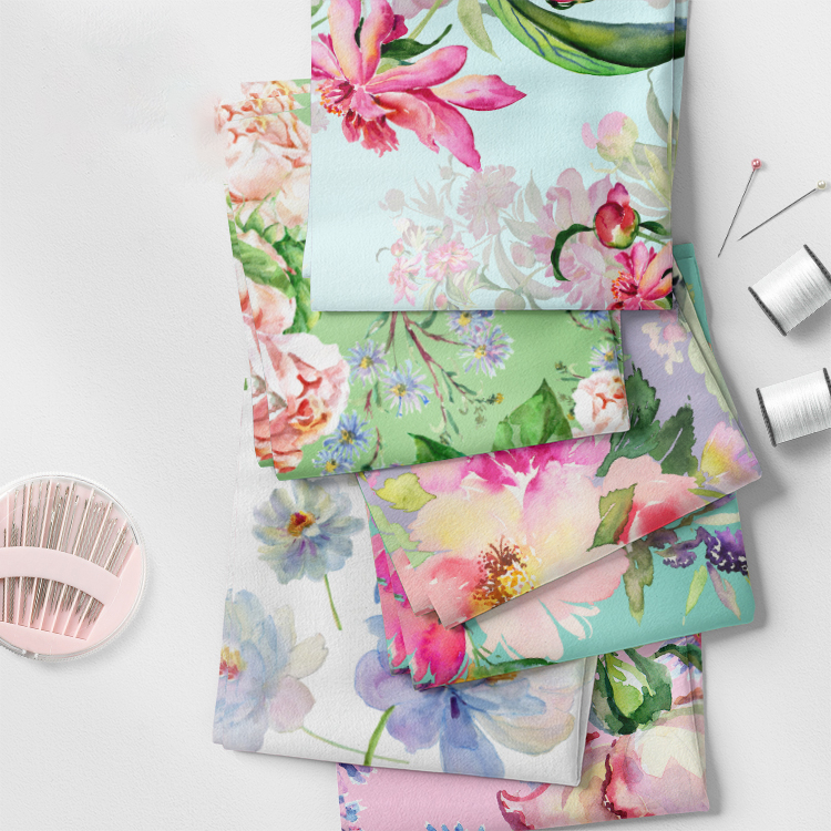 Stack of folded fabric swatches with floral prints, sewing pins and thread